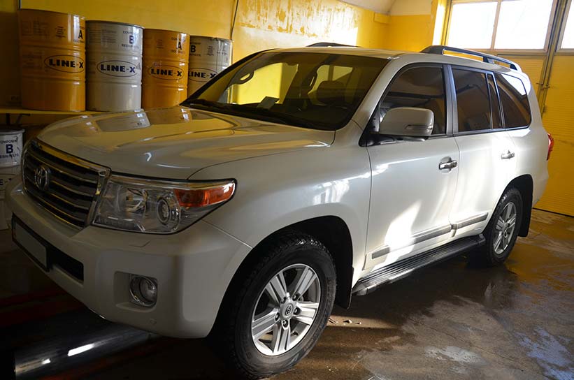 Защита кузова Toyota Land Cruiser полимерным покрытием Line-X черно-белого цвета
